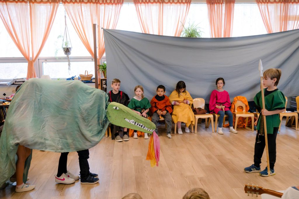 two children in a dragon costume vs. one child in a tunic with a spear