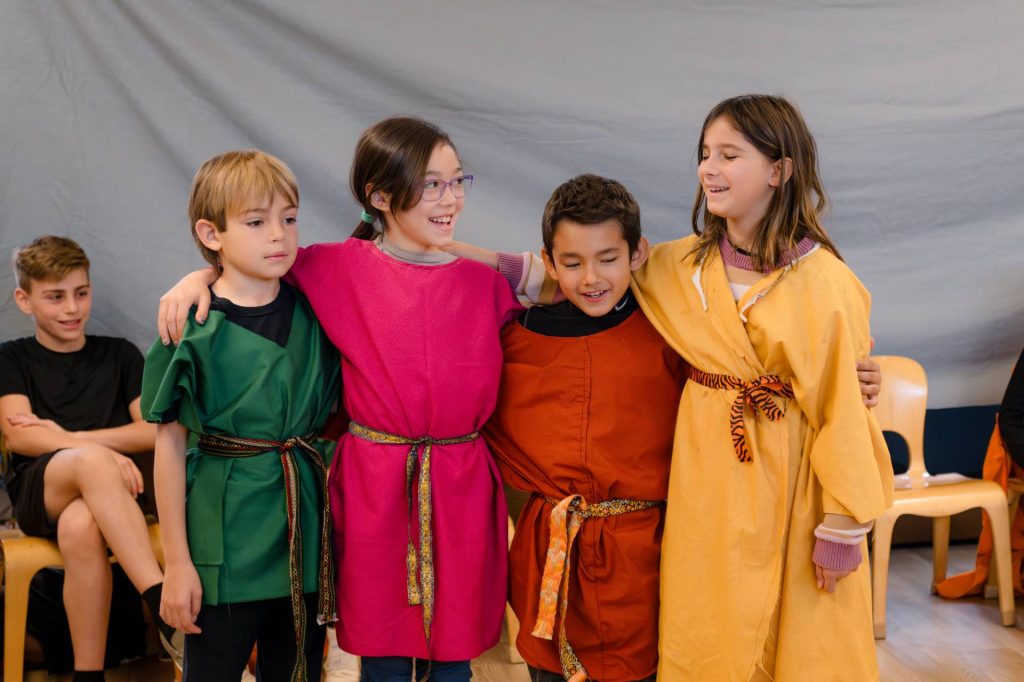 group of lower school students in costumes hugging and laughing