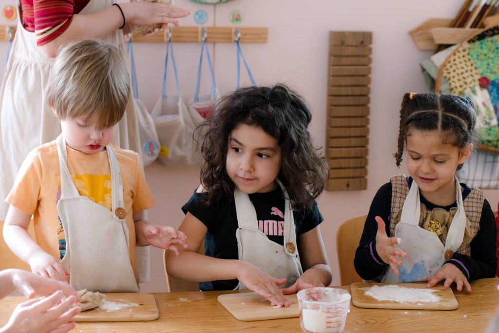 three early childhood students in aprons making food