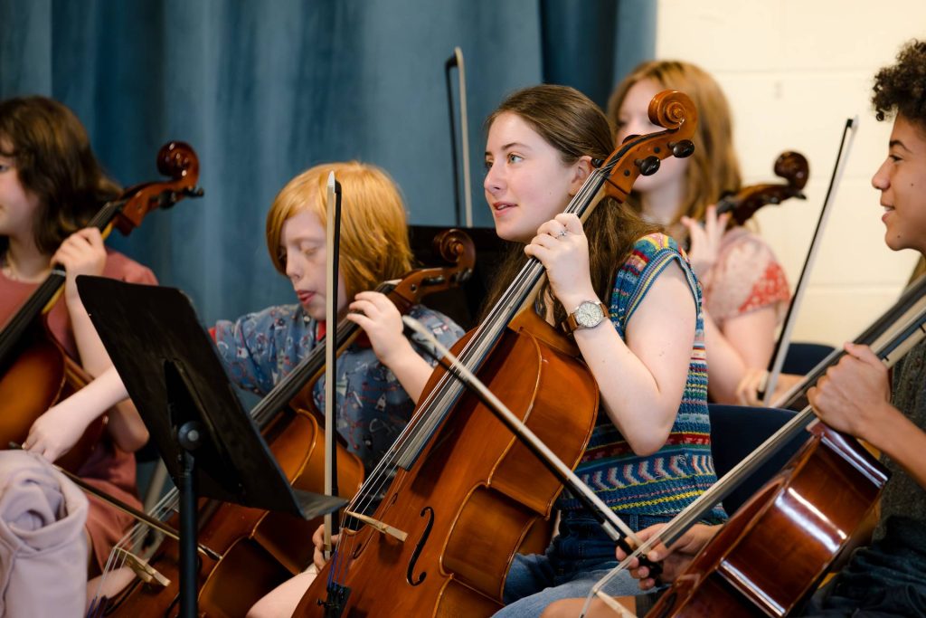 middle school students playing cello in orchestra