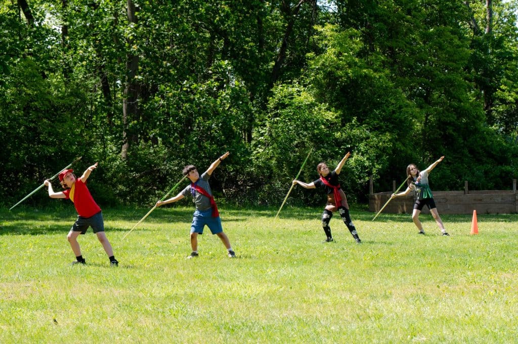 group of lower grades and middle school students throwing javelins in an open field