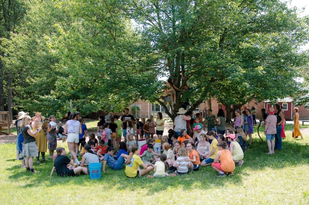 large group of river valley waldorf students sitting in the shade of a tree