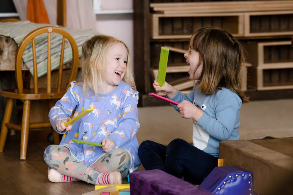 two early childhood girl students laughing together