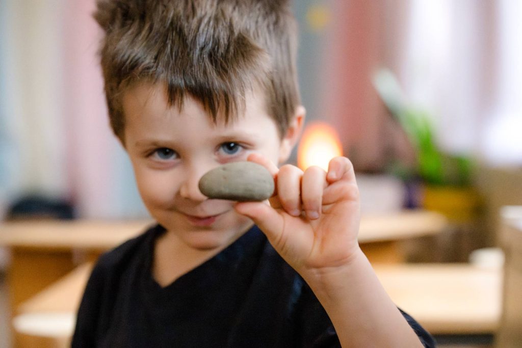 boy early childhood student holding a rock