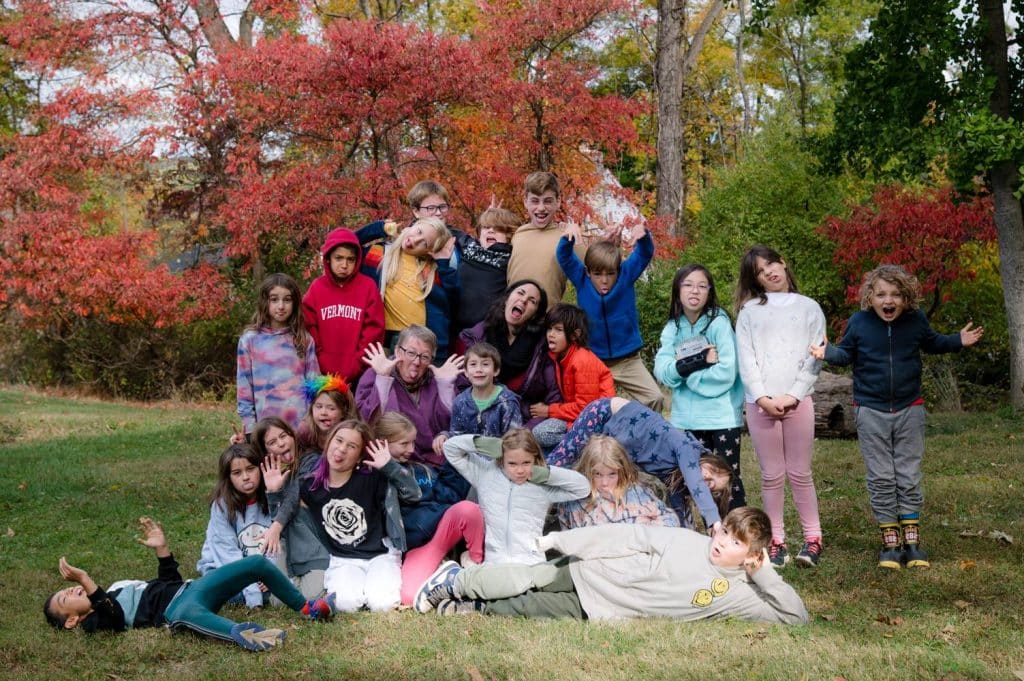 class of happy and smiling students in a fall forest