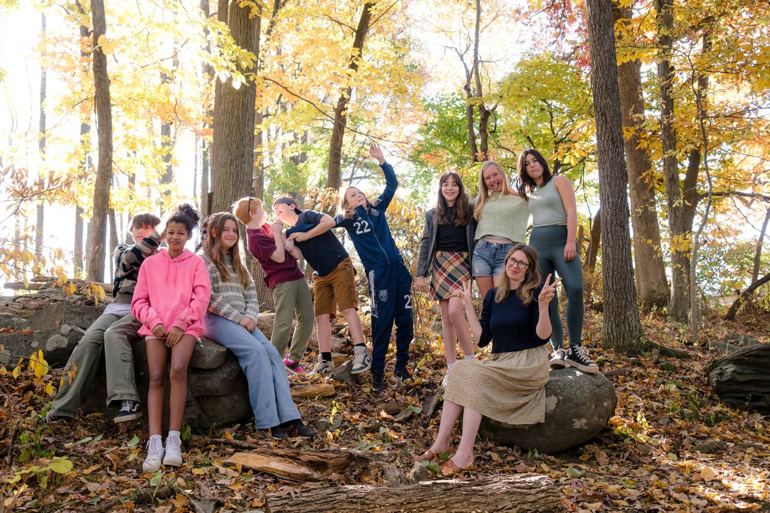 6th grade class of river valley students together in a fall forest smiling with teacher