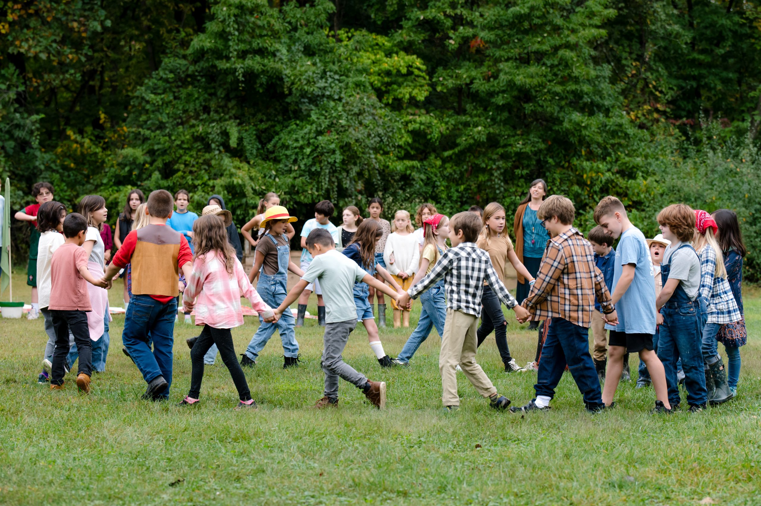 large group of students holding hands and running in a circle in a field