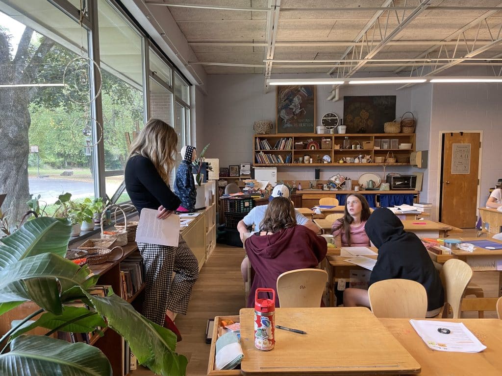 4 lower grades students sitting a table with their teacher