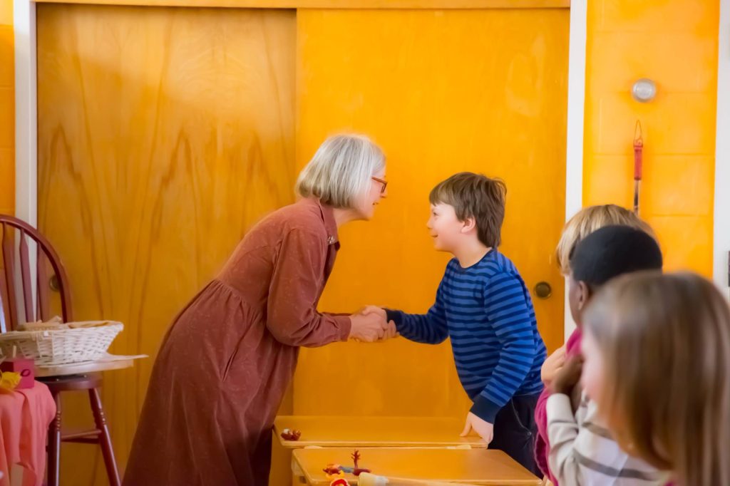 a grades school student shaking hands with a teacher