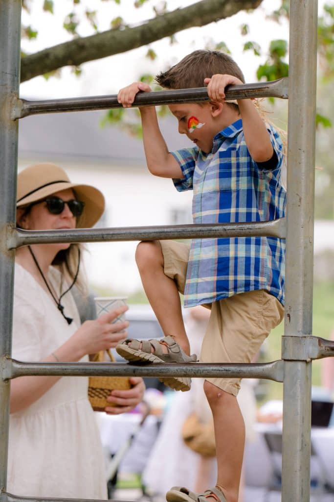 little early childhood boy student climbing up a jungle gym with his teacher
