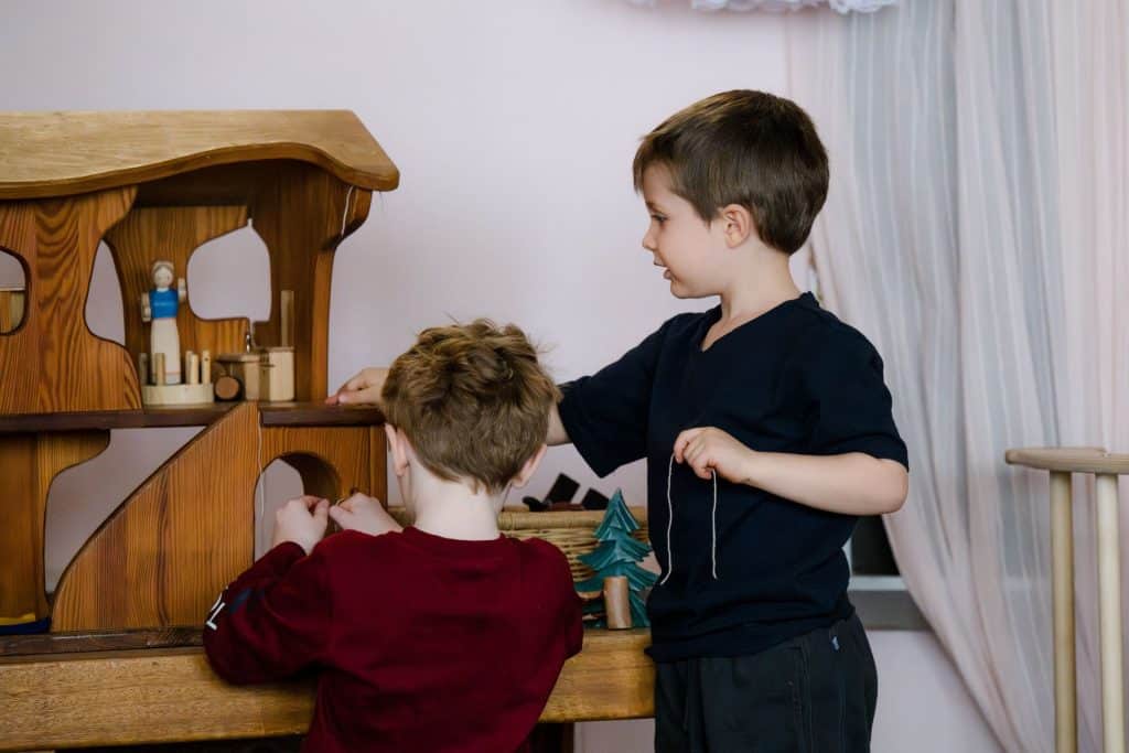 two early childhood boy students playing with wooden toys