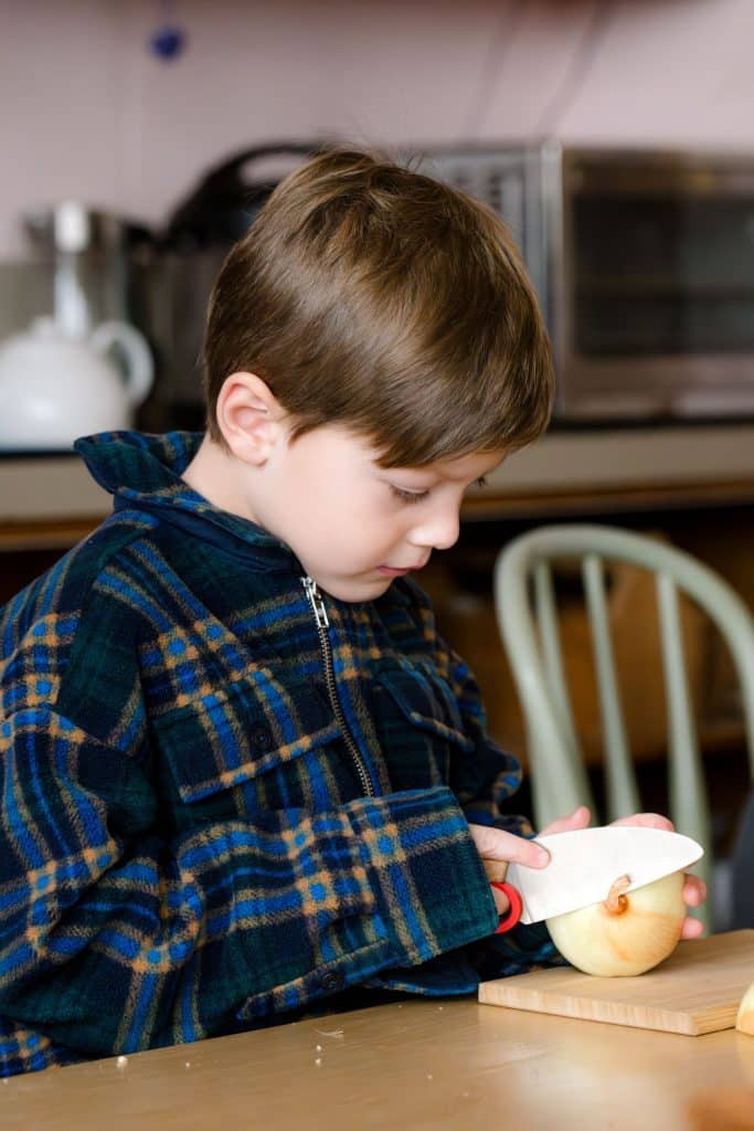 early childhood boy student preparing food with teacher