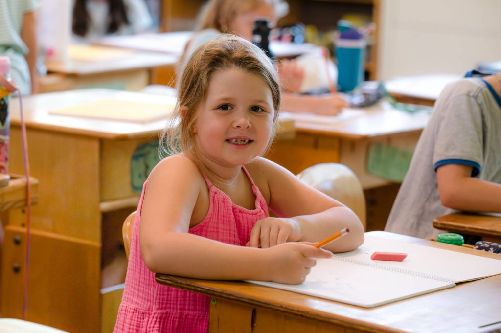 female lower school student smiling at her desk