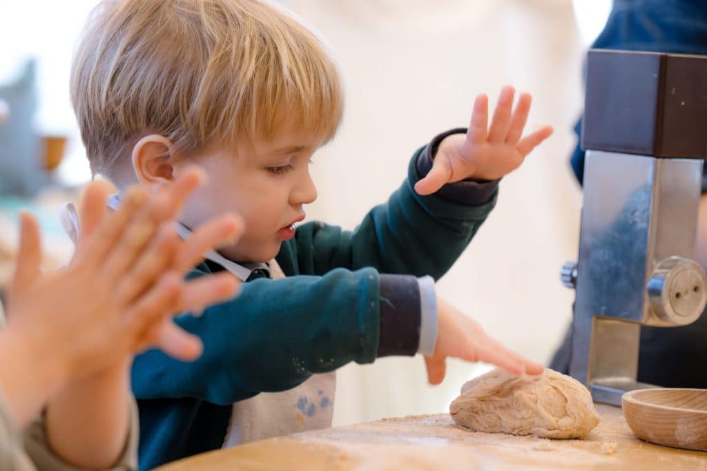 early childhood boy student with dough on a table