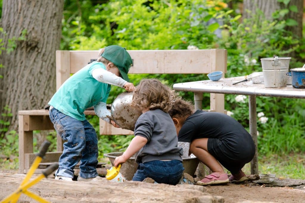 3 early childhood students digging and playing in dirt