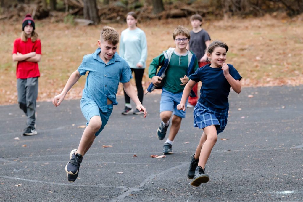 group of boy and girls lower grade students running outside on the pavement together