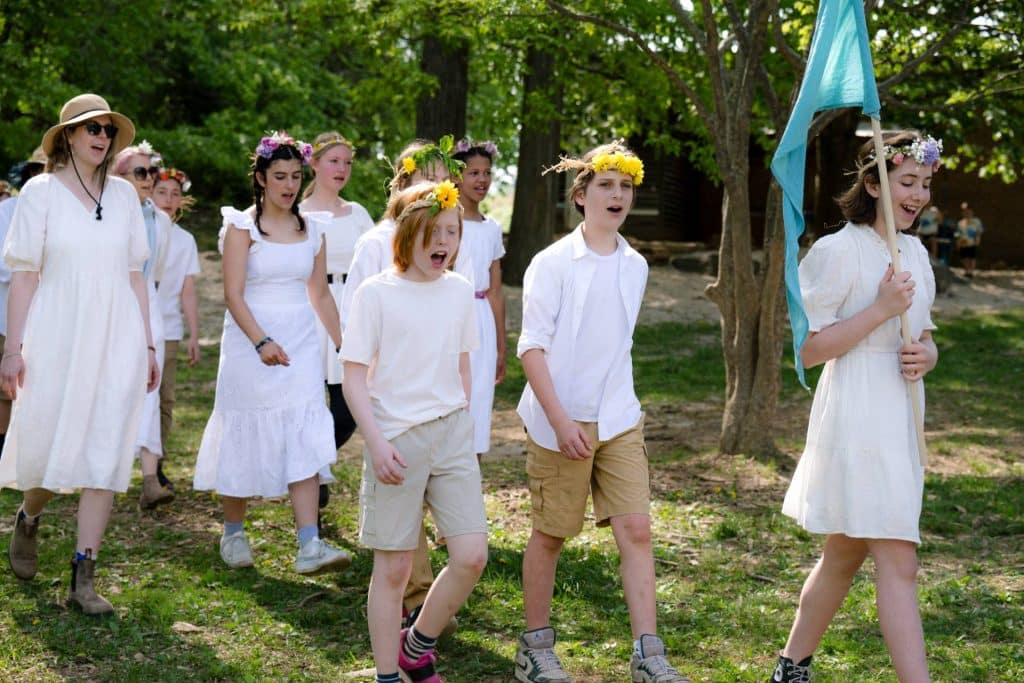 group of students wearing all white and walking outside on mayfaire day