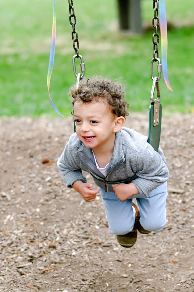young boy student swinging on a swing outside