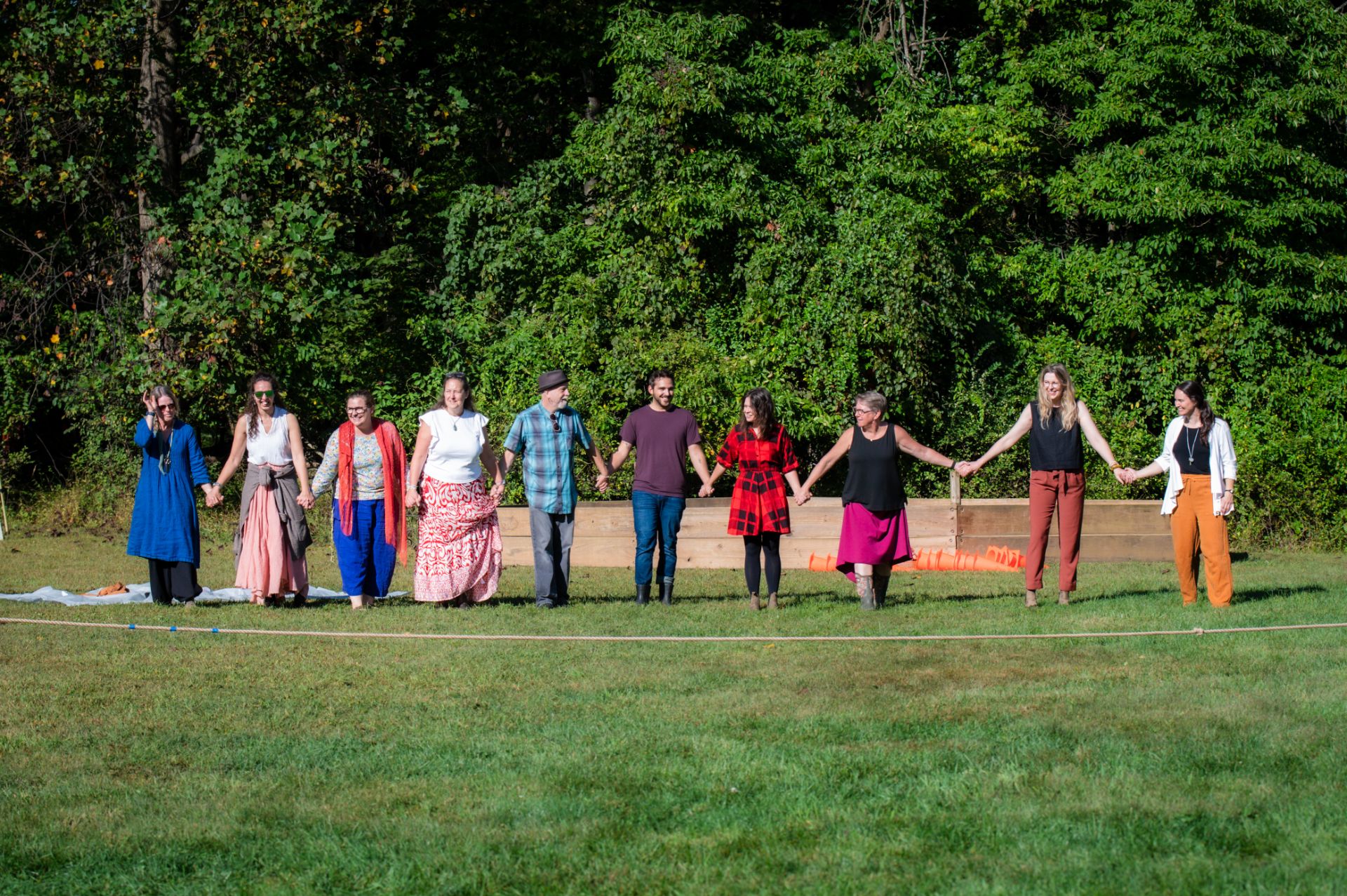 group of river valley waldorf staff and faculty holding hands outdoors in a grassy field
