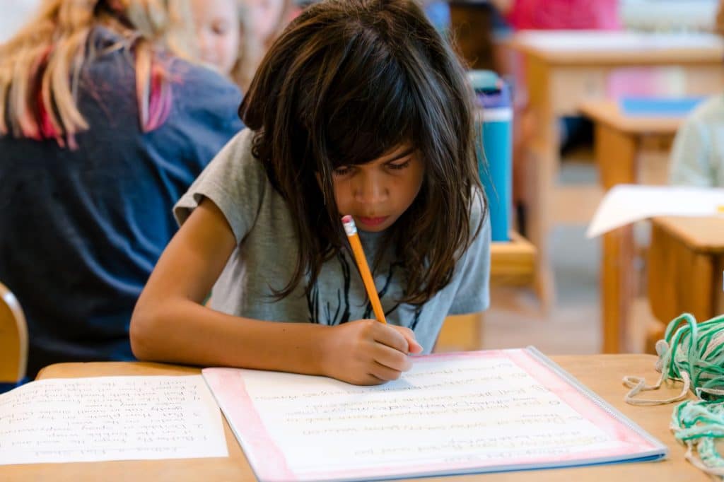 female student writing at her desk