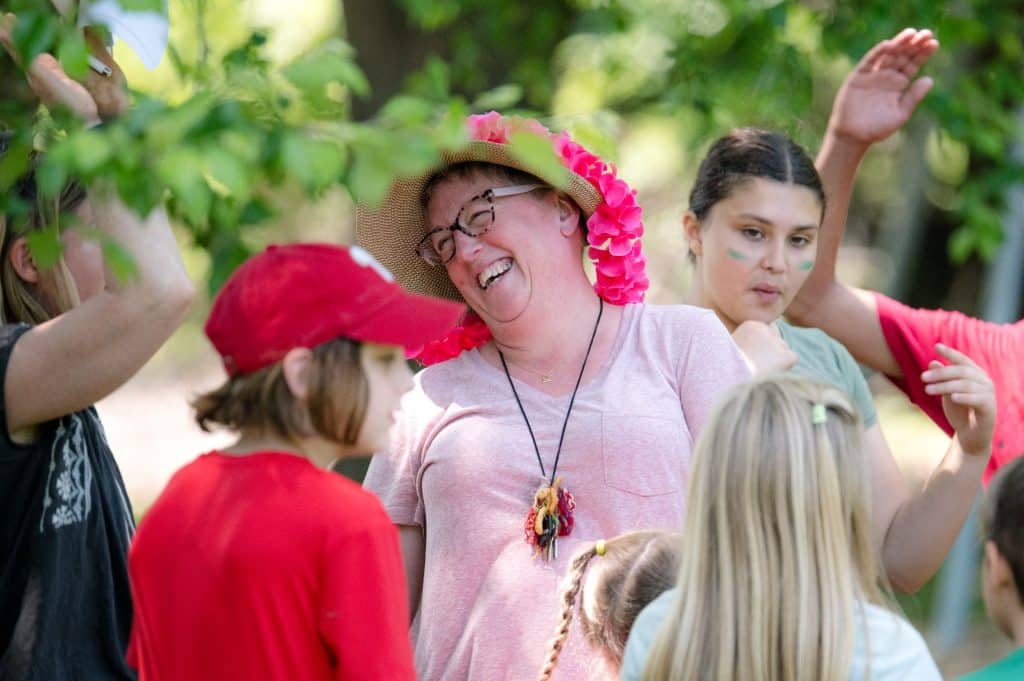 teacher smiling with a group of students outside