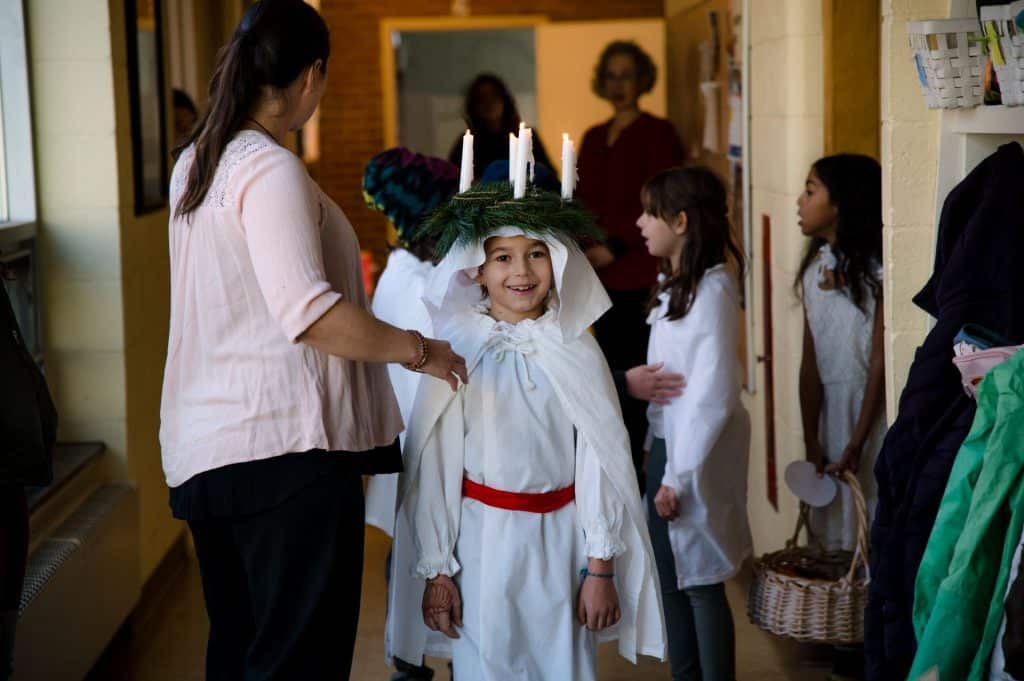 lower grades students wearing white walking in a line participating in a festival