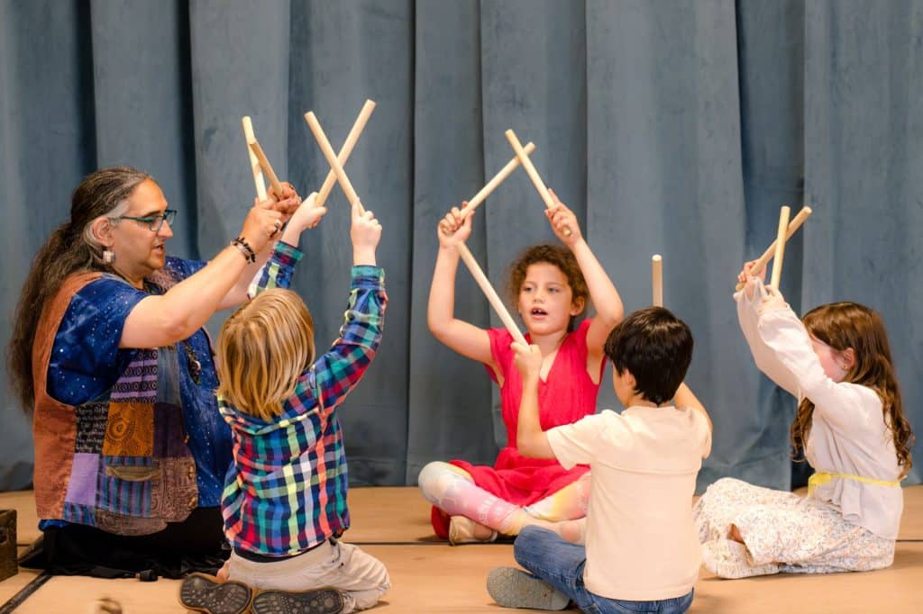 class of second graders with their teacher holding sticks in the air