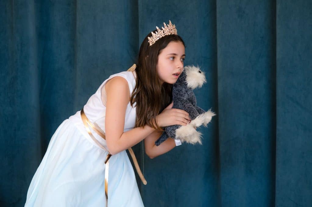 fourth and fifth graders on stage making fun faces after a dress rehearsal